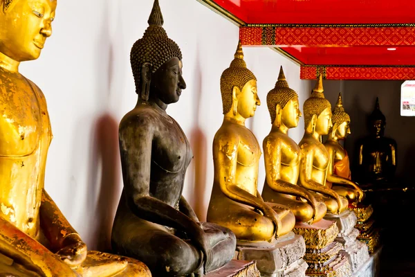Czarny posąg Buddy wśród innych złoty — Zdjęcie stockowe