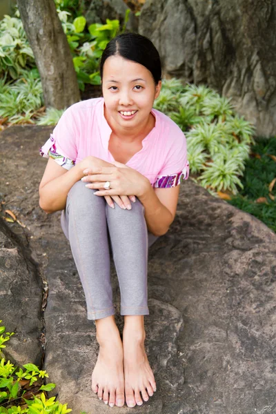 Mulher asiática sorrindo na rocha no parque — Fotografia de Stock