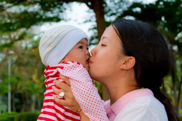 Азиатка целует своего ребенка — стоковое фото