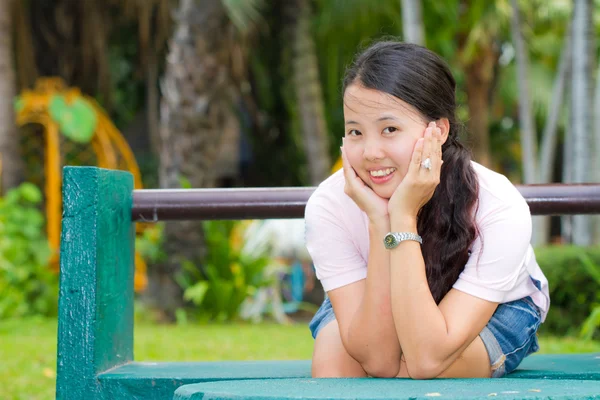 Asyalı kadın oturuyor ve gülümseme bankta — Stok fotoğraf
