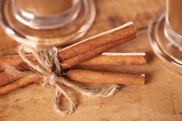 Kaneelstokjes vastgebonden en koffie op hout — Stockfoto