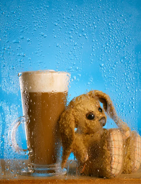stock image Bunny and coffee latte behind rainy window, shallow dof on glass
