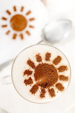 Coffee latte with frothy milk and cocoa sun in tall glass