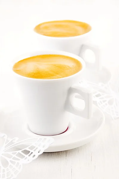 Кофе эспрессо в белых чашках и блюдцах, белый деревянный стол — стоковое фото