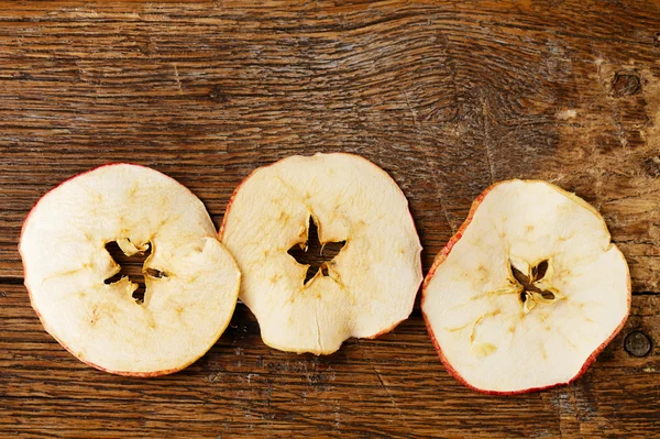 Three dried apples slices on old wooden table — Stock Photo, Image