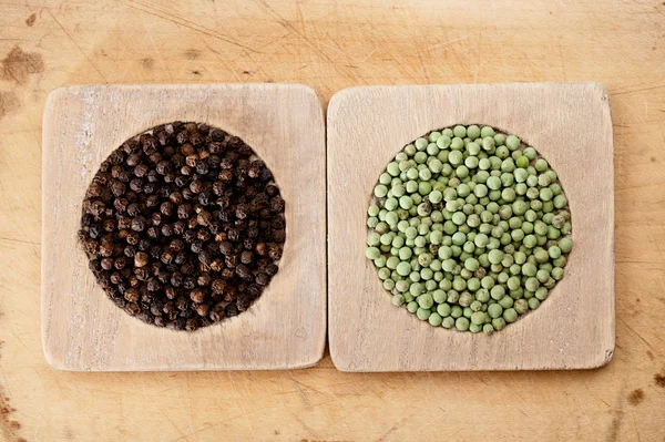 Green and black peppercorns in wooden bowls, shallow dof — Stock Photo, Image