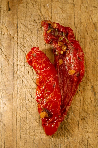 Dva kousky sušených rajčat na starém dřevěném pozadí — Stock fotografie