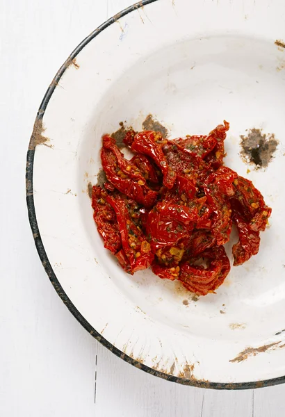Sun-dried tomatoes with olive oil in an old enamel plate — Stock Photo, Image