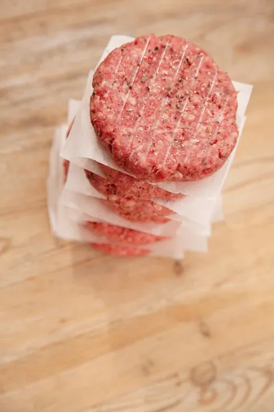 Raw burgers for hamburgers, in a pile on wood — Stock Photo, Image