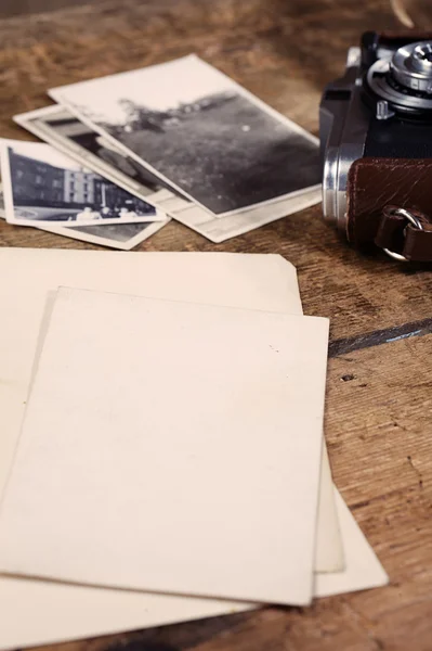 Ein paar alte Fotos und eine alte Kamera auf einem Holztisch — Stockfoto