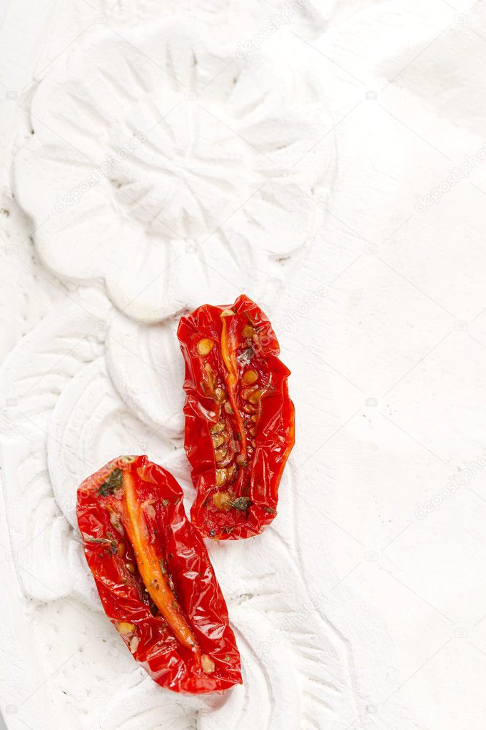 Sun-dried tomatoes with olive oil in an old white wooden backgr