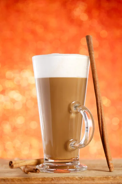 Coffee latte with cinnamon sticks, red glitter backdrop, shallow — Stock Photo, Image