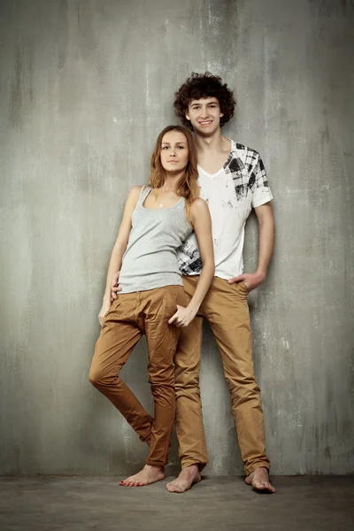 Retrato artístico de una pareja joven sobre un fondo gris y textural — Foto de Stock