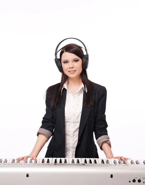 Young girl in a jacket and headphones playing a synthesizer, iso — Stock Photo, Image