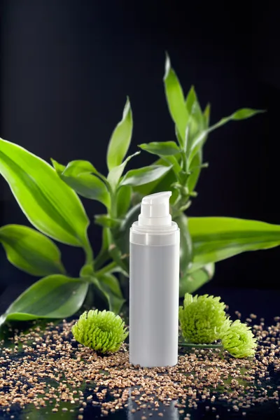 Feuchtigkeitscreme für das Gesicht zwischen Bambusblättern und Blüten — Stockfoto