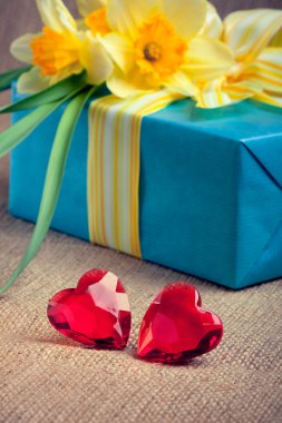 Two red glass hearts with a gift box and flowers clipart