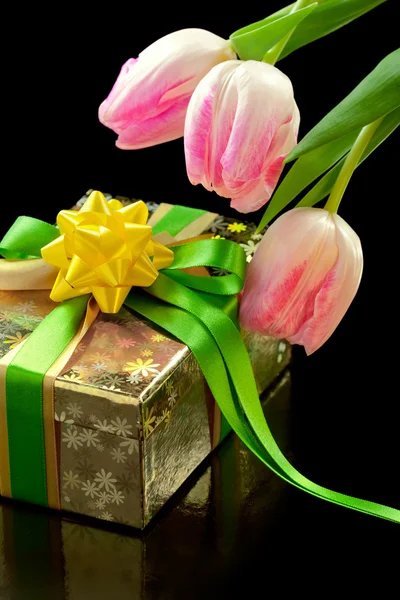 Růžové tulipány a krabičky na černém pozadí — Stock fotografie
