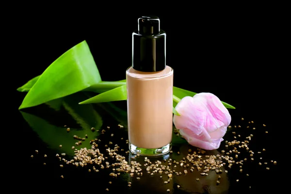 Closeup shot of foundation cream with a flower, isolated on blac — Stock Photo, Image