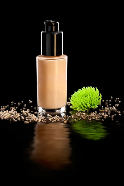 Closeup shot of foundation cream with a flower, on black — Stock Photo, Image