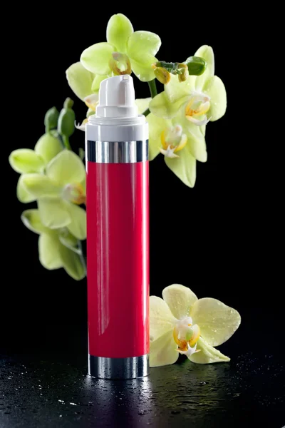 Face/body care concept: bottle of cream/lotion/serum with orchid — Stock Photo, Image