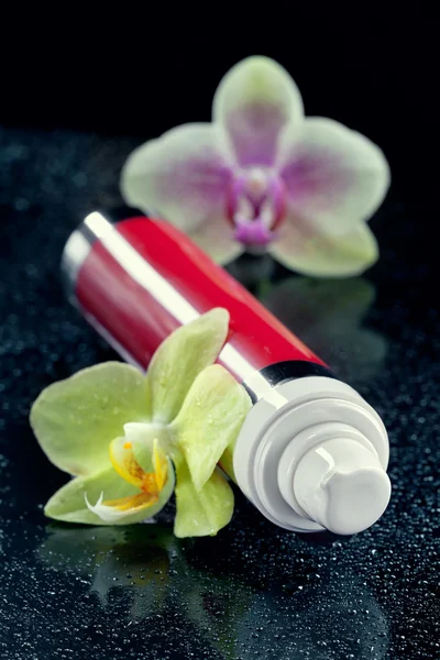 Μπουκάλι κρέμα προσώπου/λοσιόν με orchid λουλούδια, closeup, πυροβόλησε, ὁ — Φωτογραφία Αρχείου