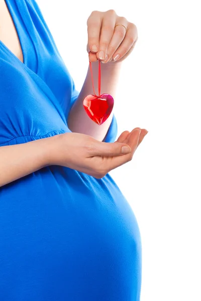 Mujer embarazada sosteniendo el corazón sobre su barriga, disparo de primer plano — Foto de Stock