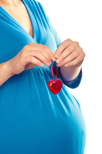 Беременная женщина держит сердце над животом, крупным планом. — стоковое фото