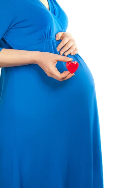 Беременная женщина держит маленькое милое сердце над животом — стоковое фото