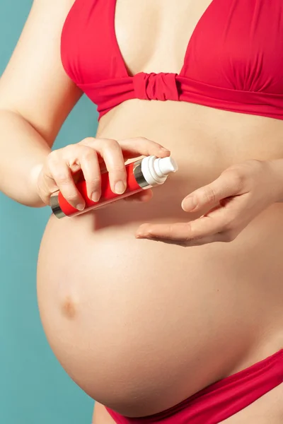 Cuidado de la piel en el embarazo: mujer embarazada joven usando crema corporal — Foto de Stock