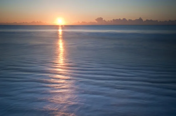 Smuk lavvande strand pulserende solopgang - Stock-foto