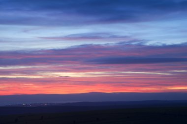 Fiery Winter sunset over town at night with colored layers clipart