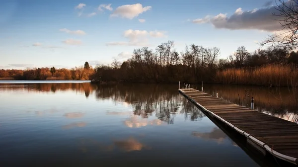 Hermoso paisaje al atardecer sobre embarcadero en el lago —  Fotos de Stock
