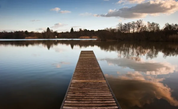Hermoso paisaje al atardecer sobre embarcadero en el lago — Foto de Stock