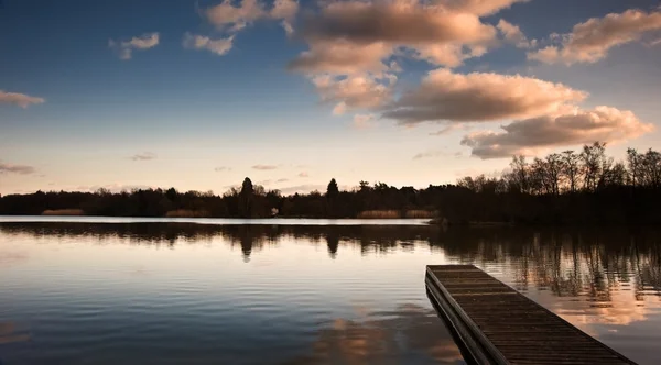 Hermoso paisaje al atardecer sobre embarcadero en el lago — Foto de Stock