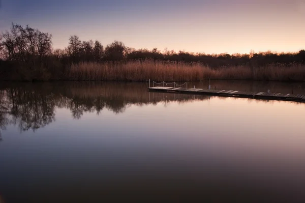 Bela tarde da noite pôr do sol paisagem sobre molhe no lago — Fotografia de Stock