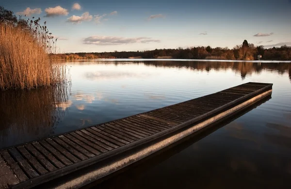 Hermoso paisaje al atardecer sobre embarcadero en el lago —  Fotos de Stock