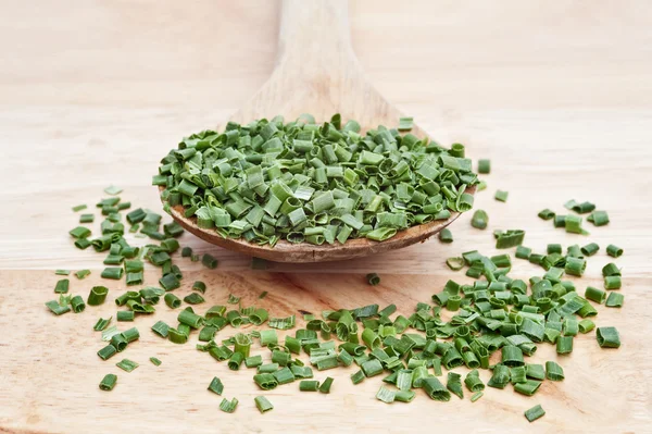 Chopped chives on wooden serving spoon with selective focus — Stock Photo, Image