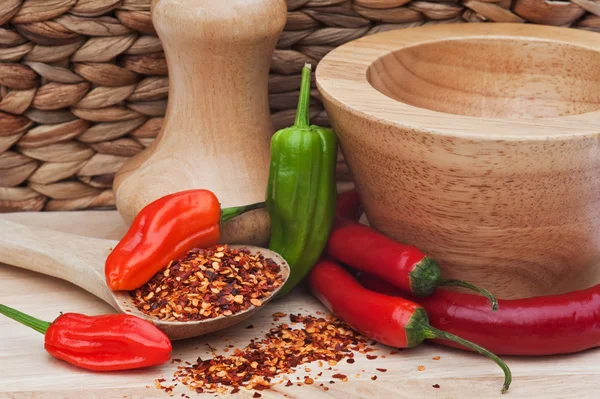 Crushed and whole chilli peppers in rustic kitchen setting — Stock Photo, Image