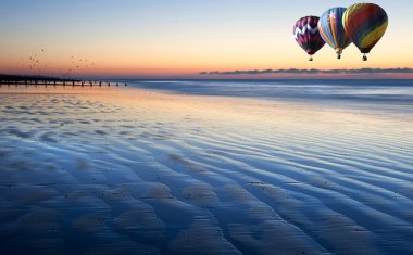 Hot air balloons over beautiful low tide beach vibrant sunrise