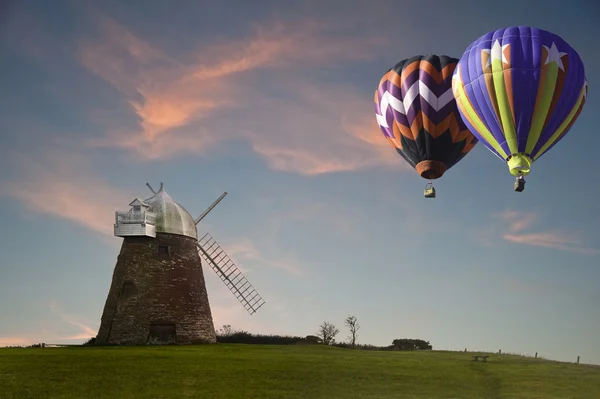 Moinho de vento velho tradicional no por do sol com balões de ar quente — Fotografia de Stock