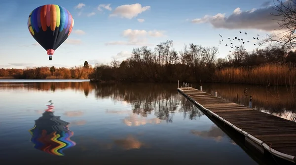 stock image Hot air balloon over sunset lake with jetty