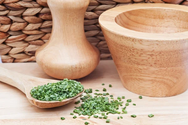 Chopped chives in rustic kitchen setting with wooden pestle and — Stock Photo, Image