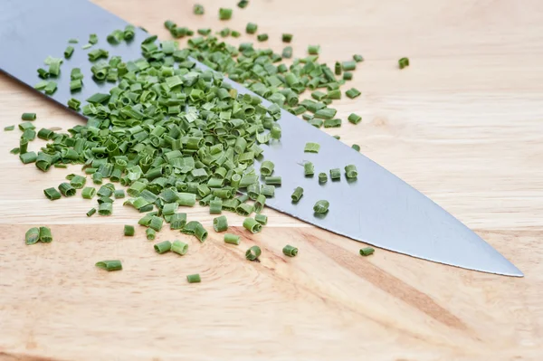 stock image Chopped chives on wooden chopping board with knife