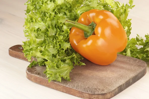 Paprika en salade op snijplank op tafel — Stockfoto