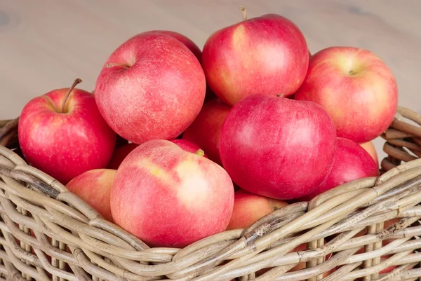 Červená jablka v košíku na stole — Stock fotografie