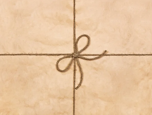 String tied in a bow on a brown recycled paper — Stock Photo, Image