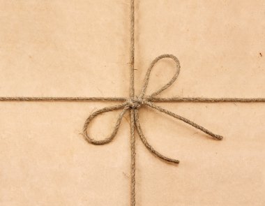 String tied in a bow on a brown recycled paper clipart