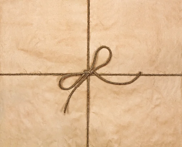 String tied in a bow on a brown recycled paper — Stock Photo, Image