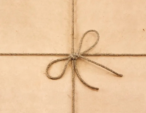 String vastgebonden in een strik op een bruin gerecycled papier — Stockfoto