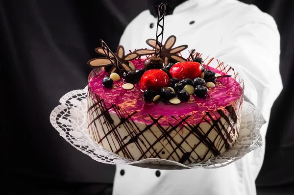 Kuchen vor dunklem Hintergrund halten — Stockfoto